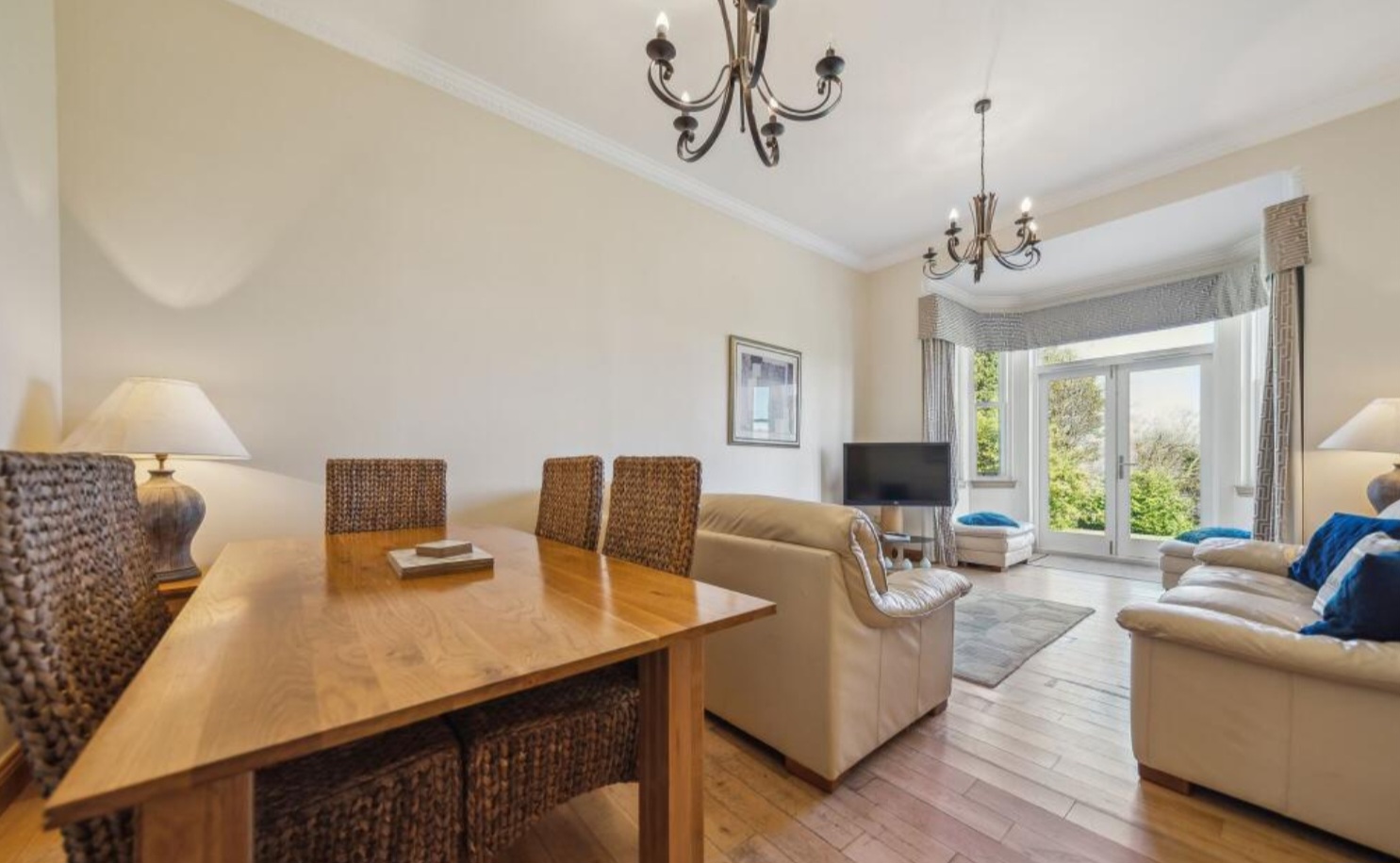 The open living and dining room at No. 15, with two sofas, an oak dining table and a television