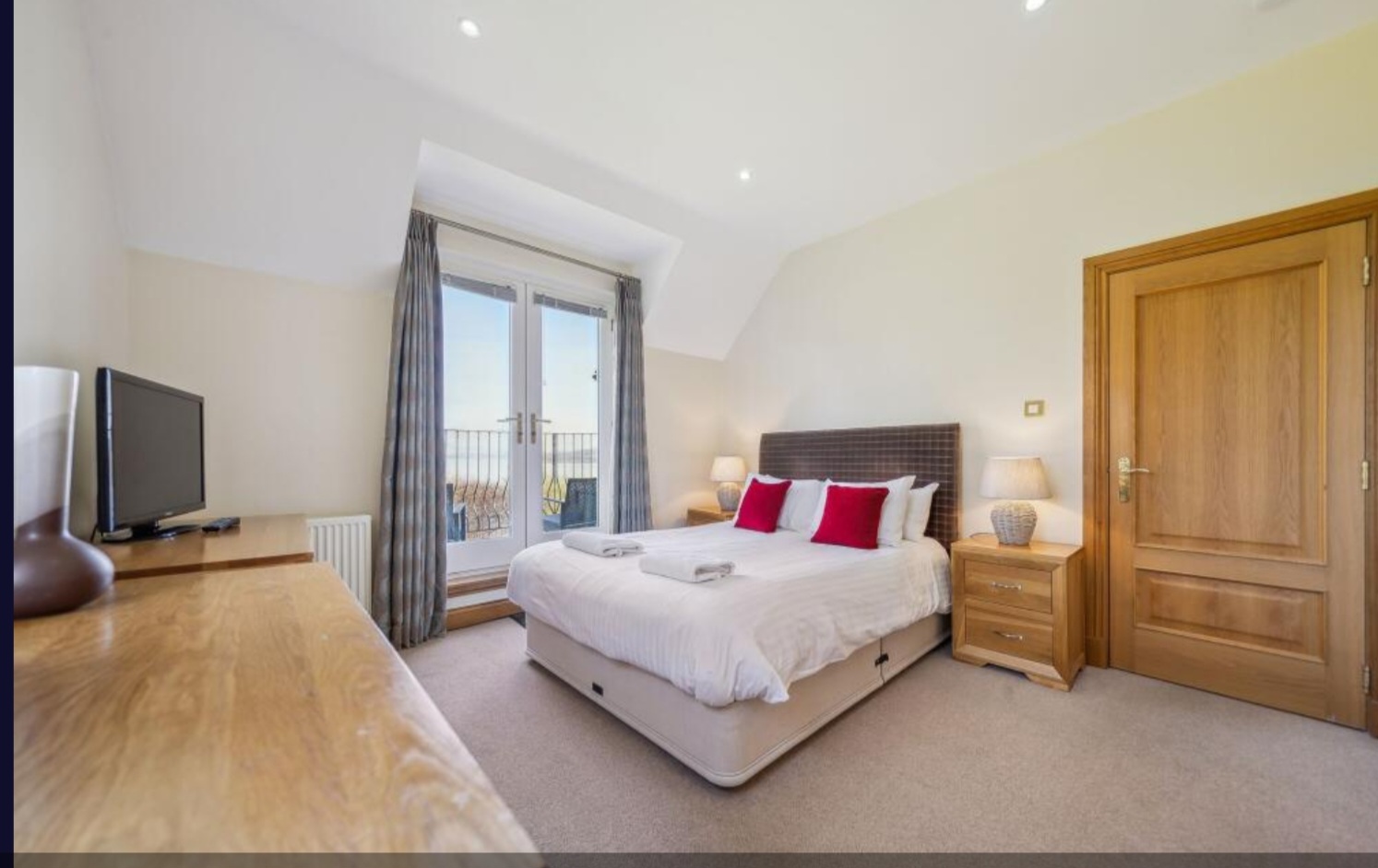 The master bedroom at No. 15, with a king-size bed and French doors opening onto the private balcony